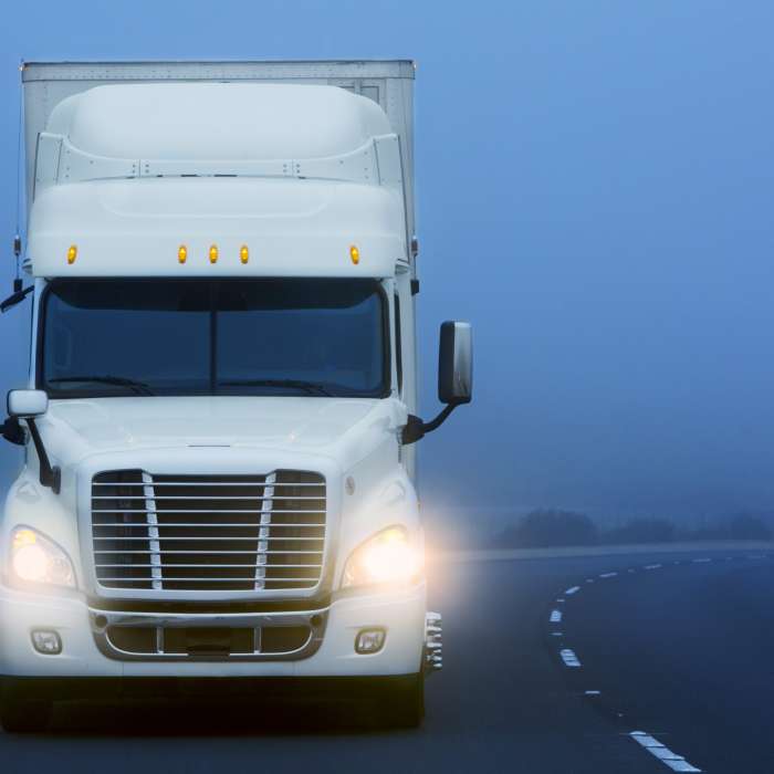 Commerical Class 8 truck being driven in the fog on a country road.